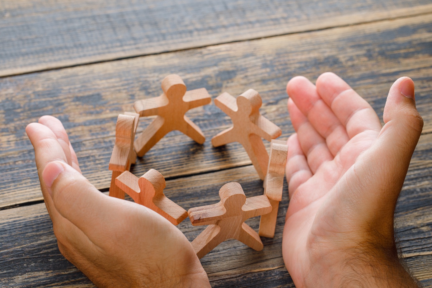 A close-up of hands around a group of wooden people