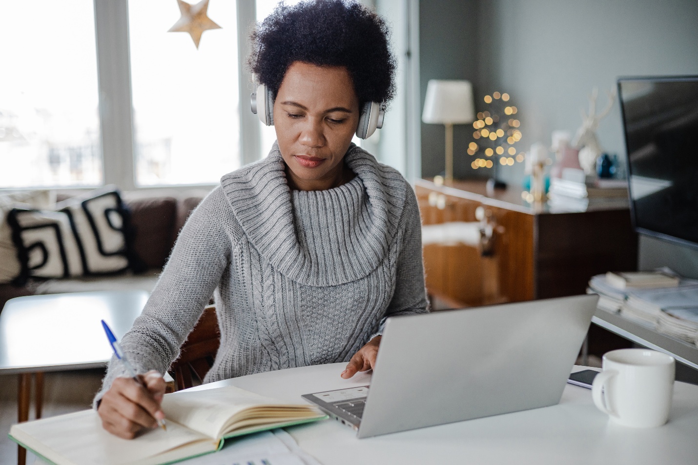 Adult at laptop writing in journal