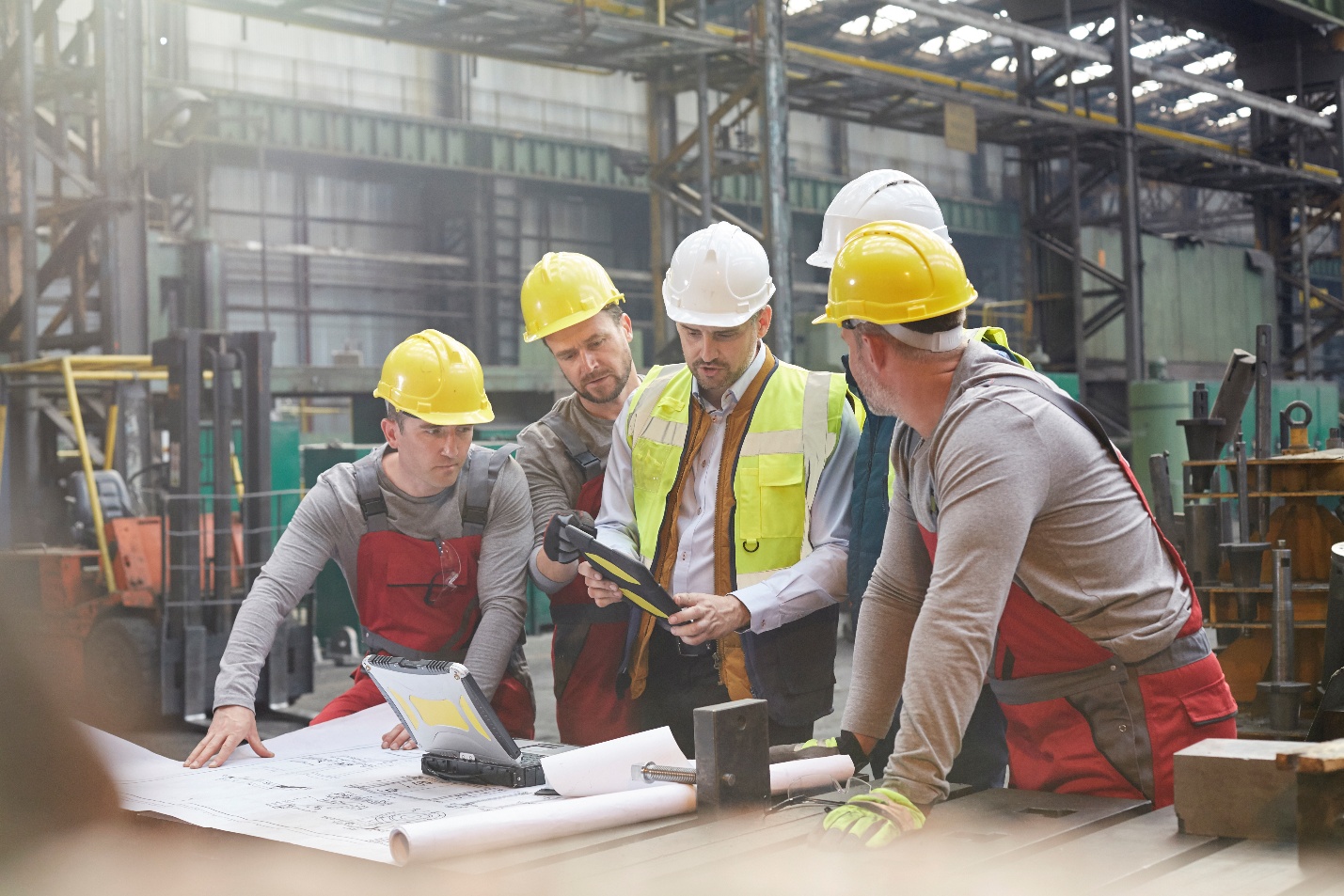 Engineers with digital tablet and blueprints in a factory