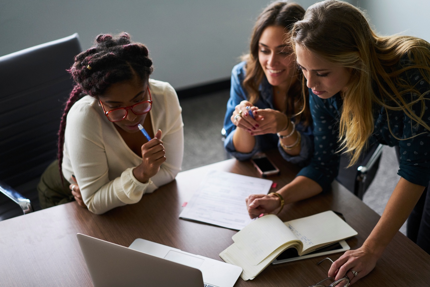 Three women gathered around laptop